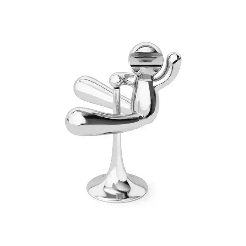 Metallic sculpture of a person sitting on a chair on a white background