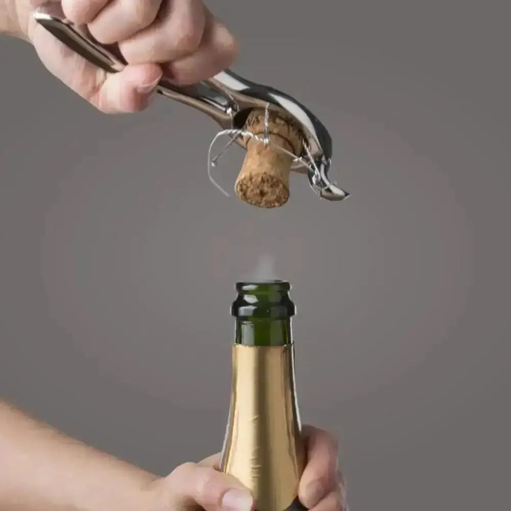 Hand using a bottle opener to remove a cork from a champagne bottle on a gray background