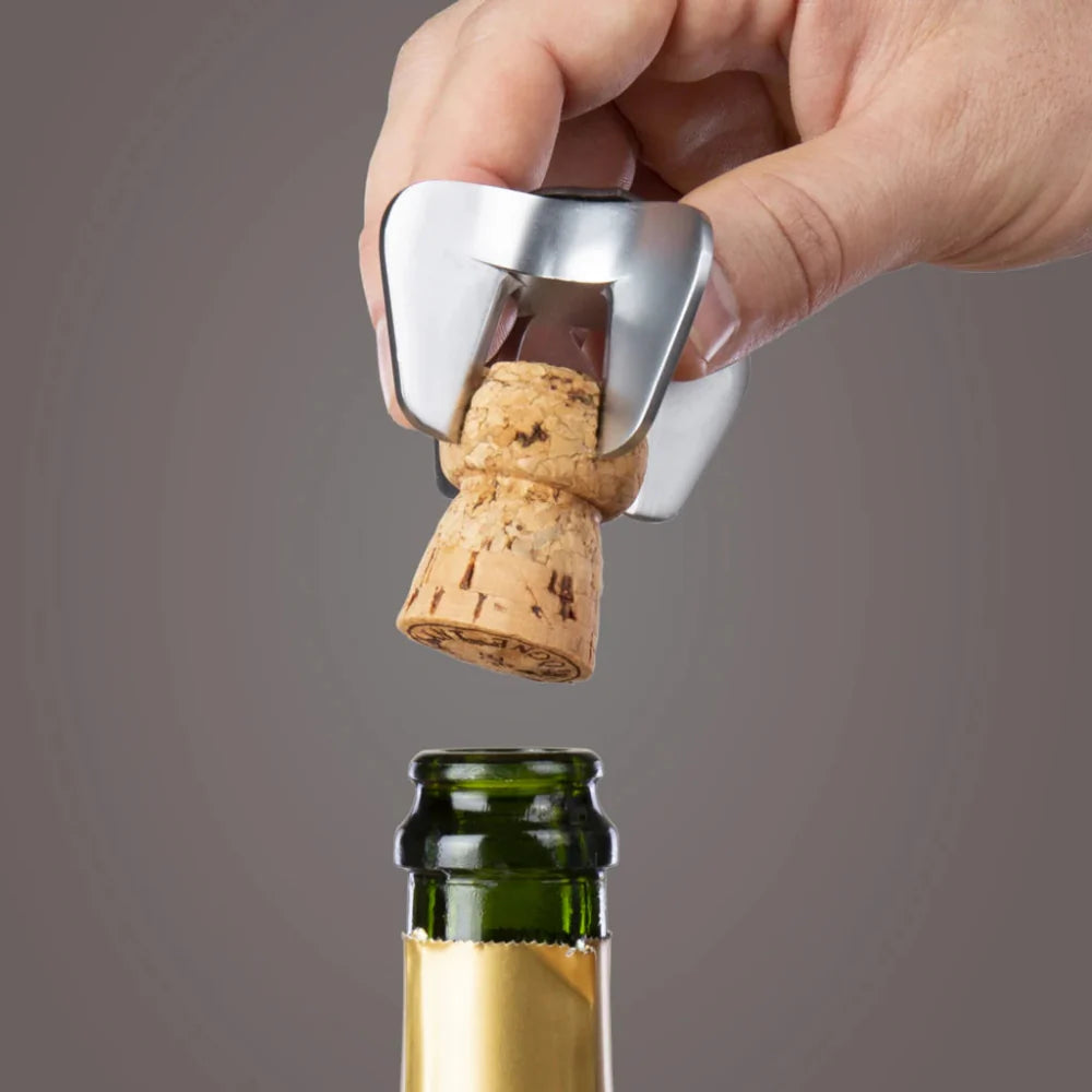 Hand using a bottle opener to remove a cork from a wine bottle on a gray background