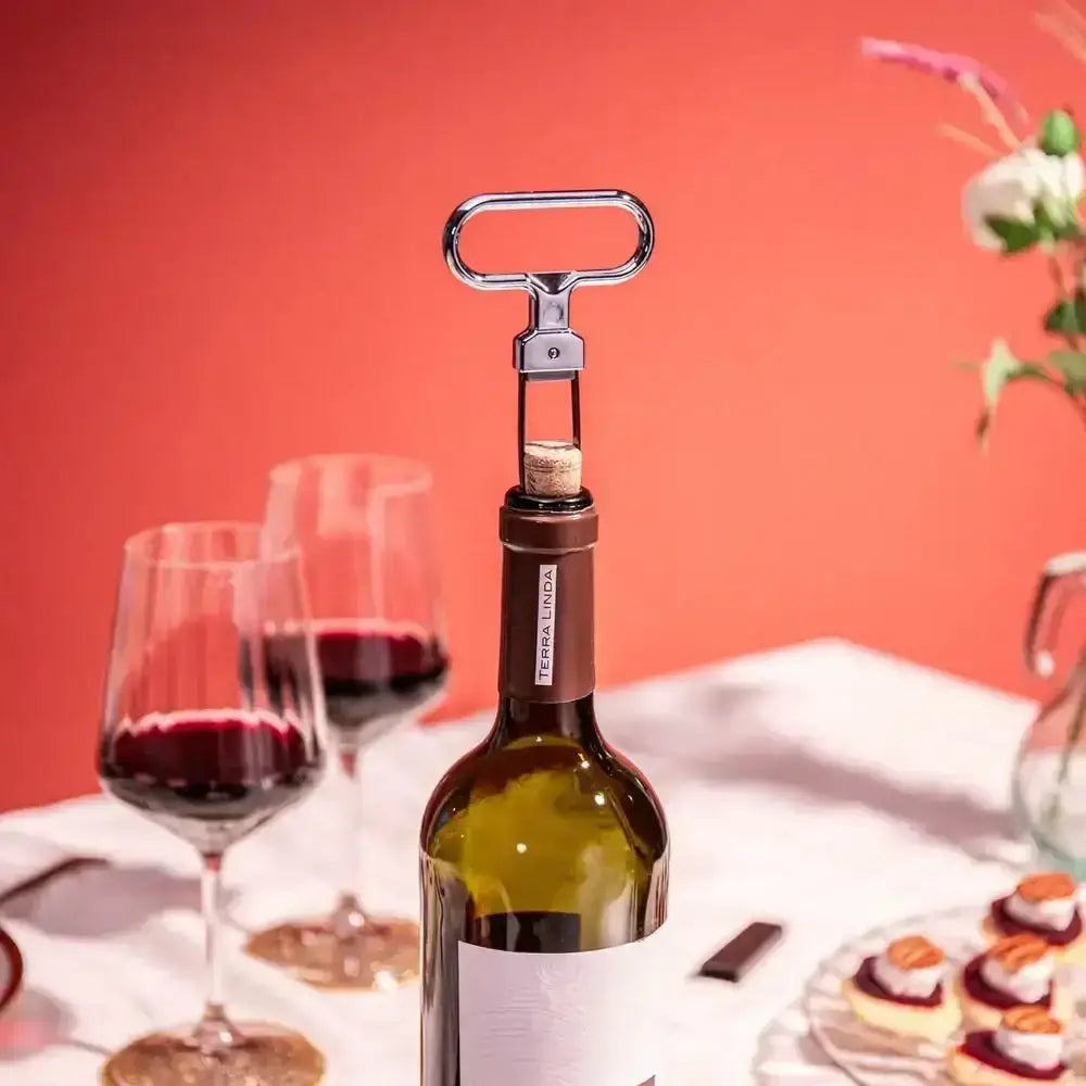 Wine bottle with corkscrew stopper, glasses of red wine, and pastries on a table.