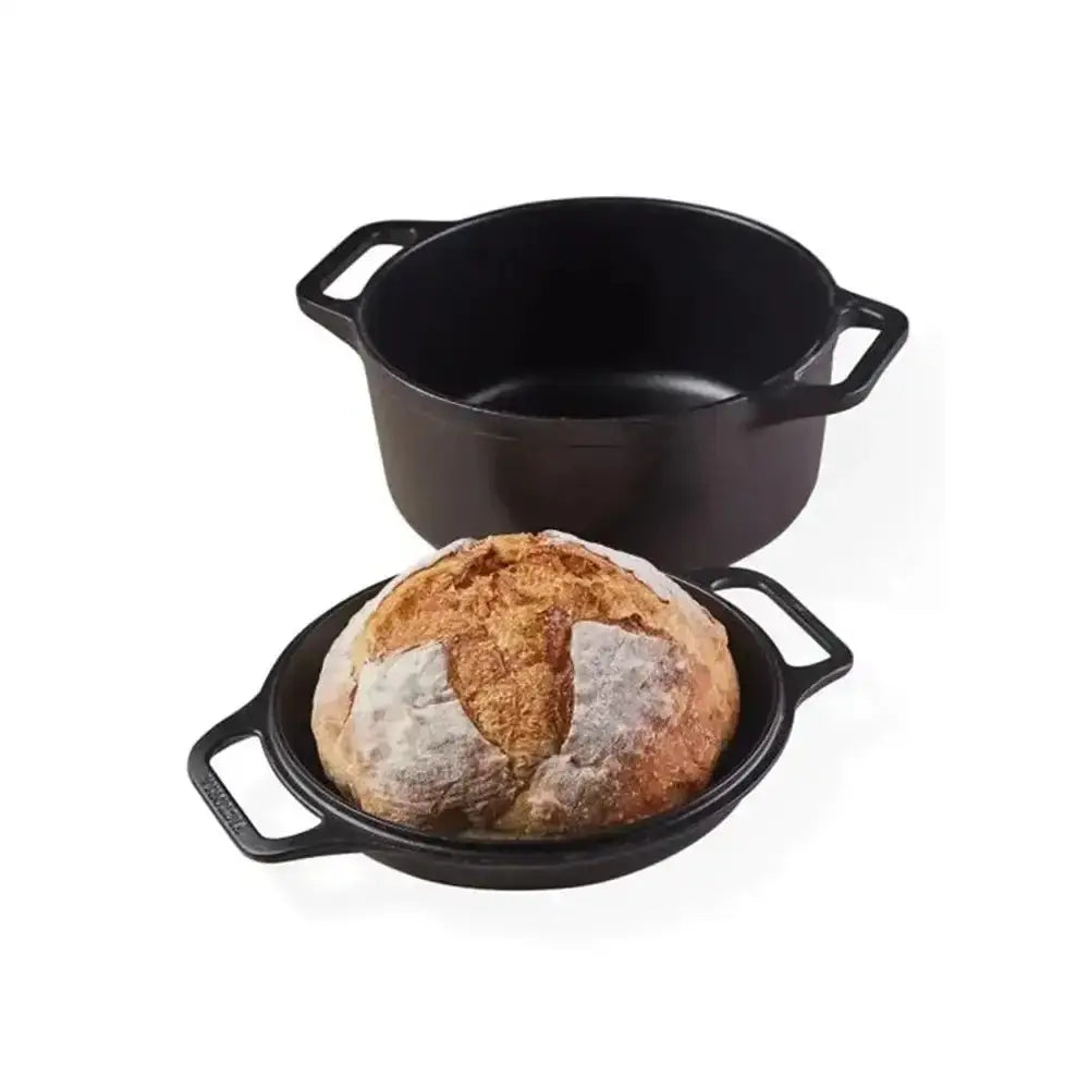 Black cast iron pot with a loaf of bread on a white background