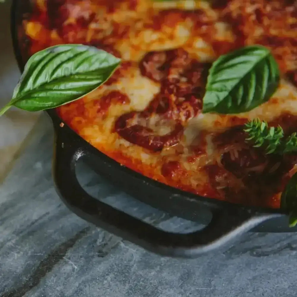 Cheesy pizza with tomato sauce and basil leaves on a stone surface