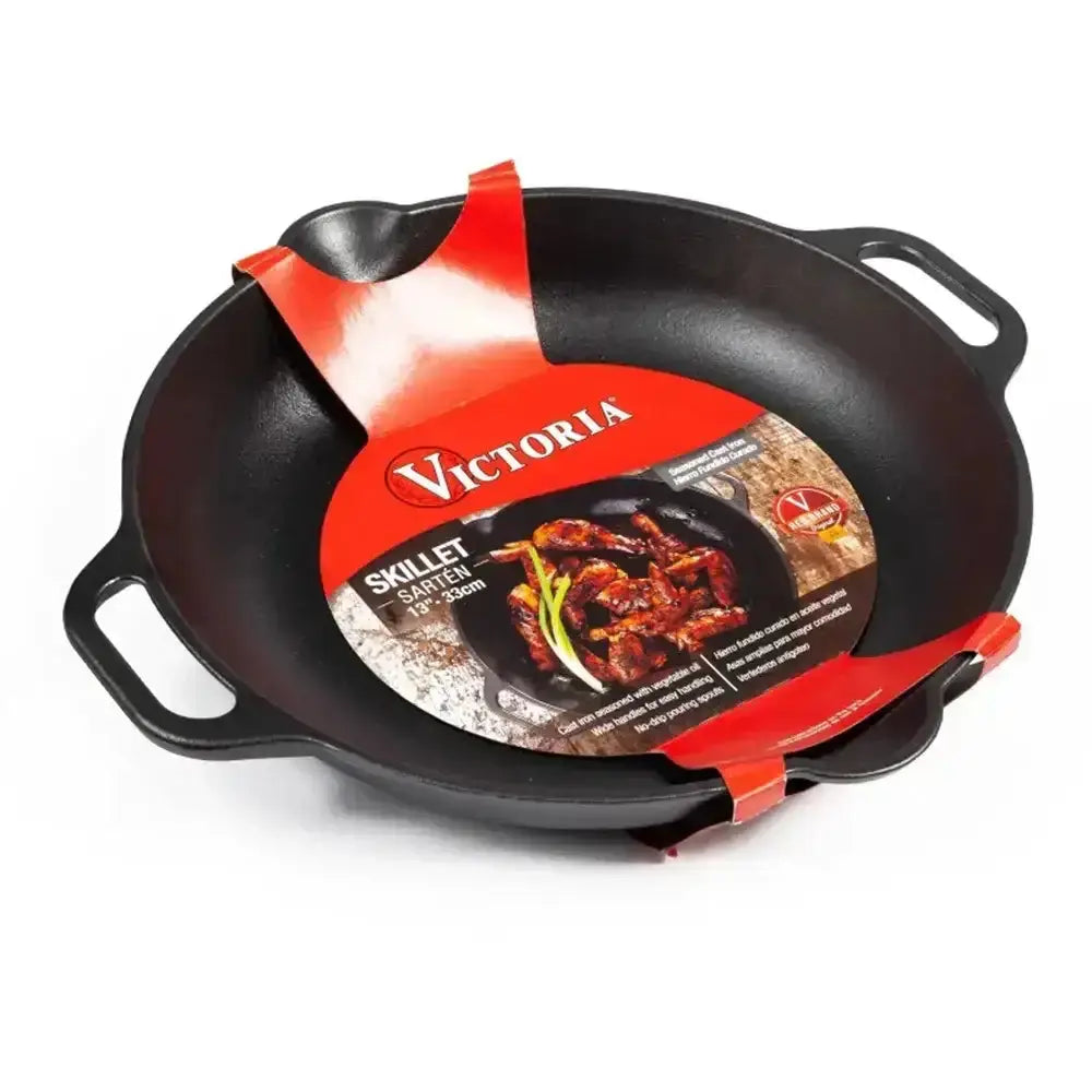 Black cast iron skillet with red Victoria brand packaging on a white background