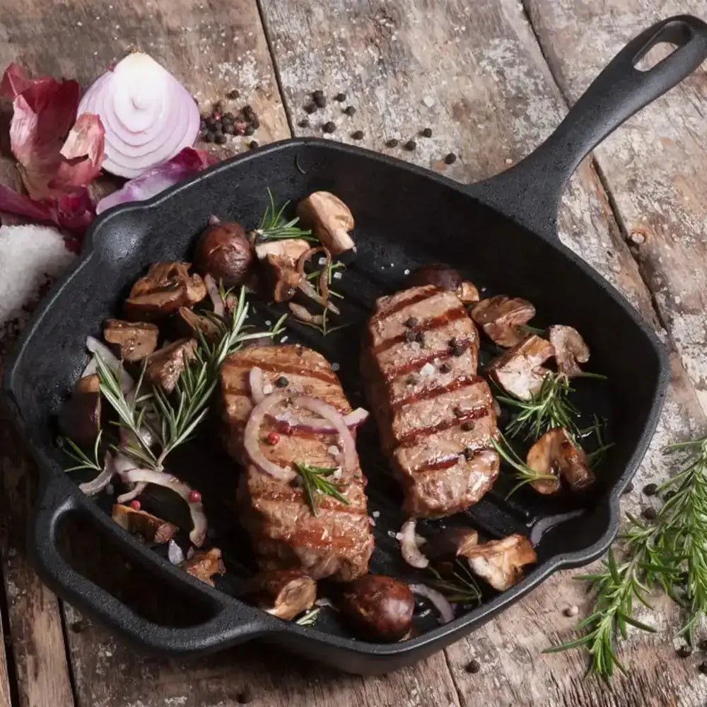 Grilled steak with mushrooms and herbs in a cast iron skillet on a wooden surface