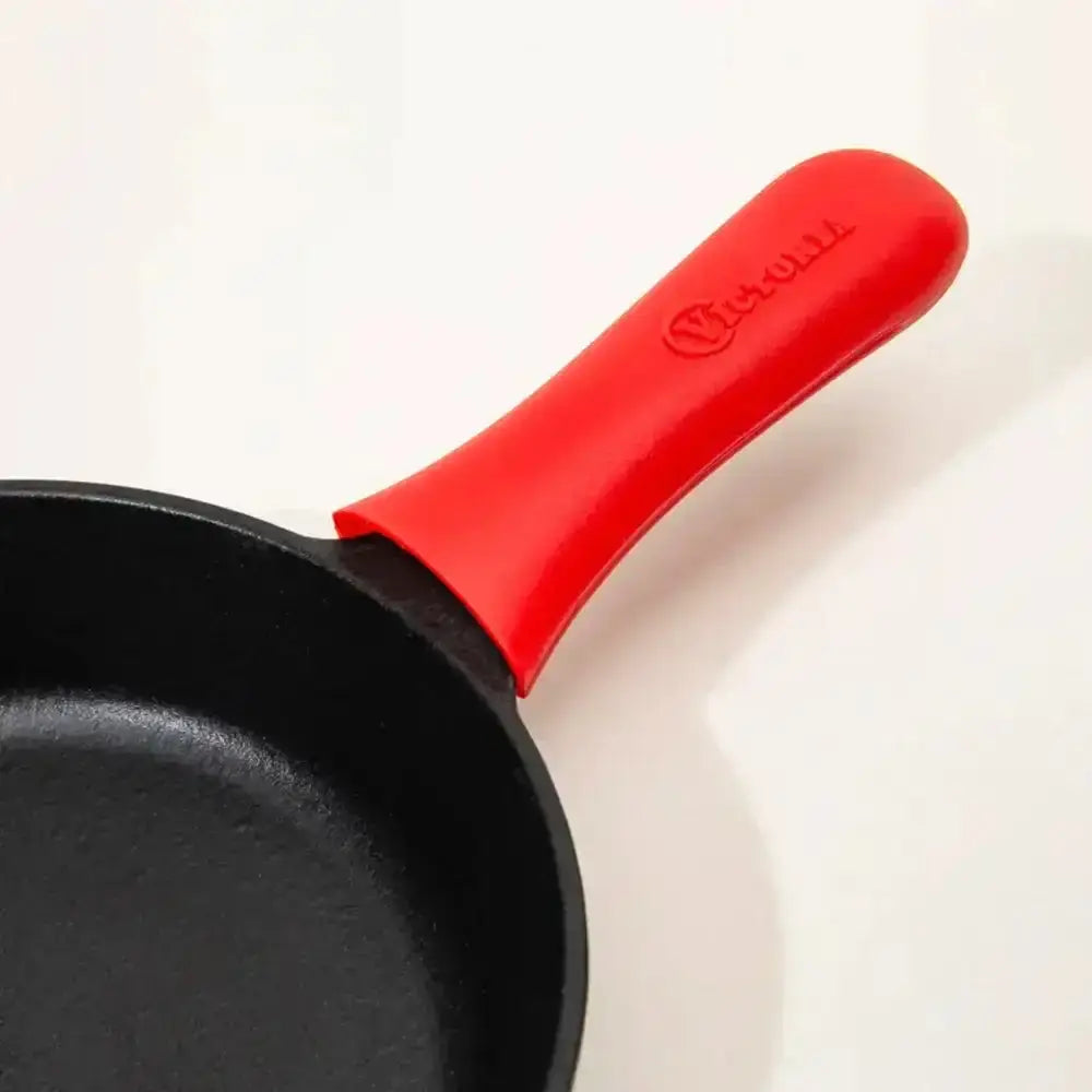 Black frying pan with a large red silicone handle