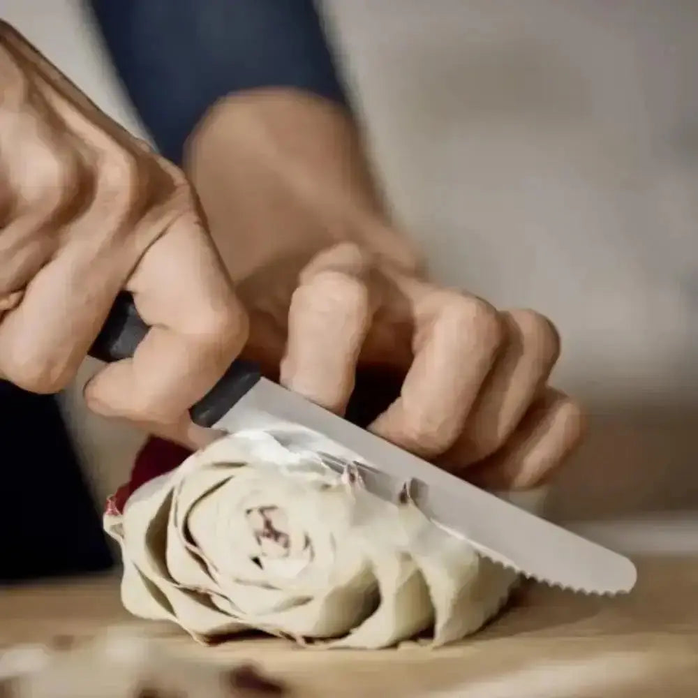 Person cutting a white rose with a knife on a wooden surface.