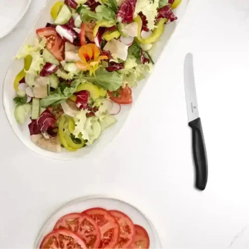 Colorful salad on a white plate with a knife on a white background