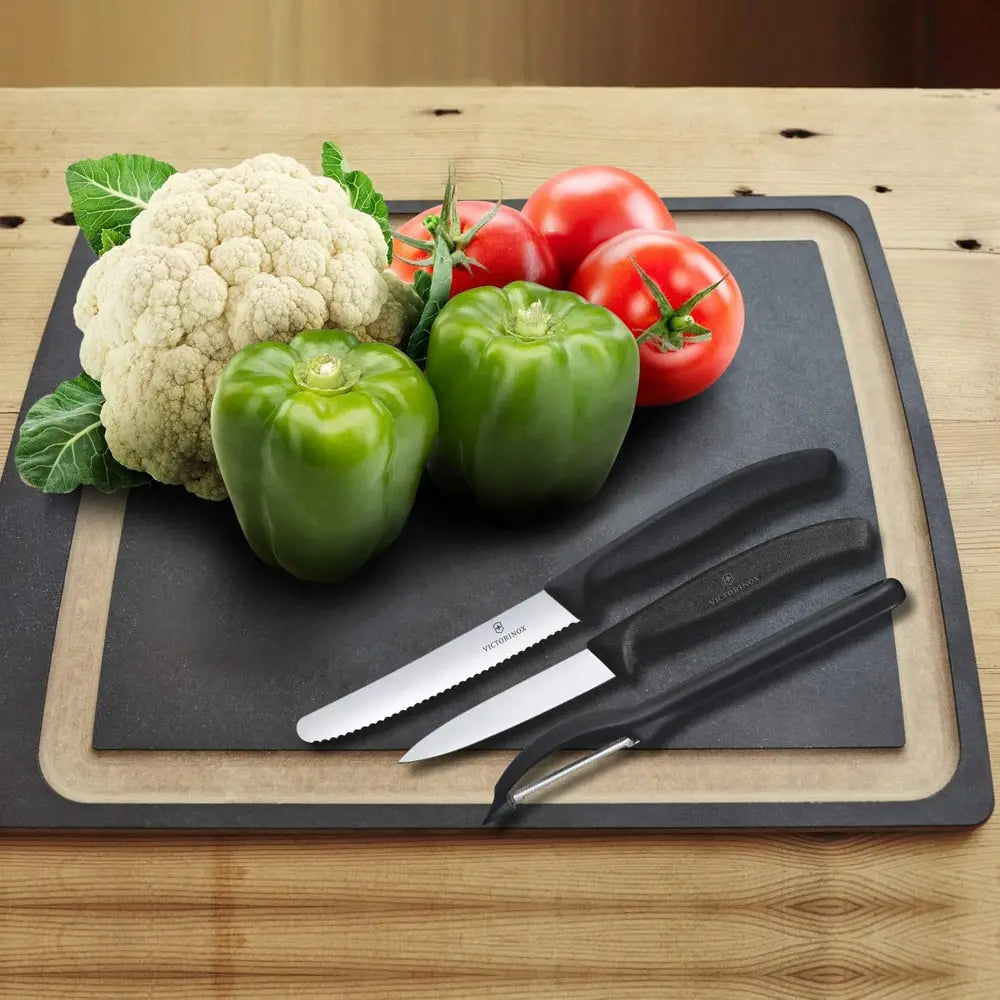 Vegetables on a cutting board with knives on a wooden surface