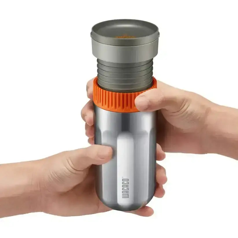 Silver and orange thermos held by a hand on a white background