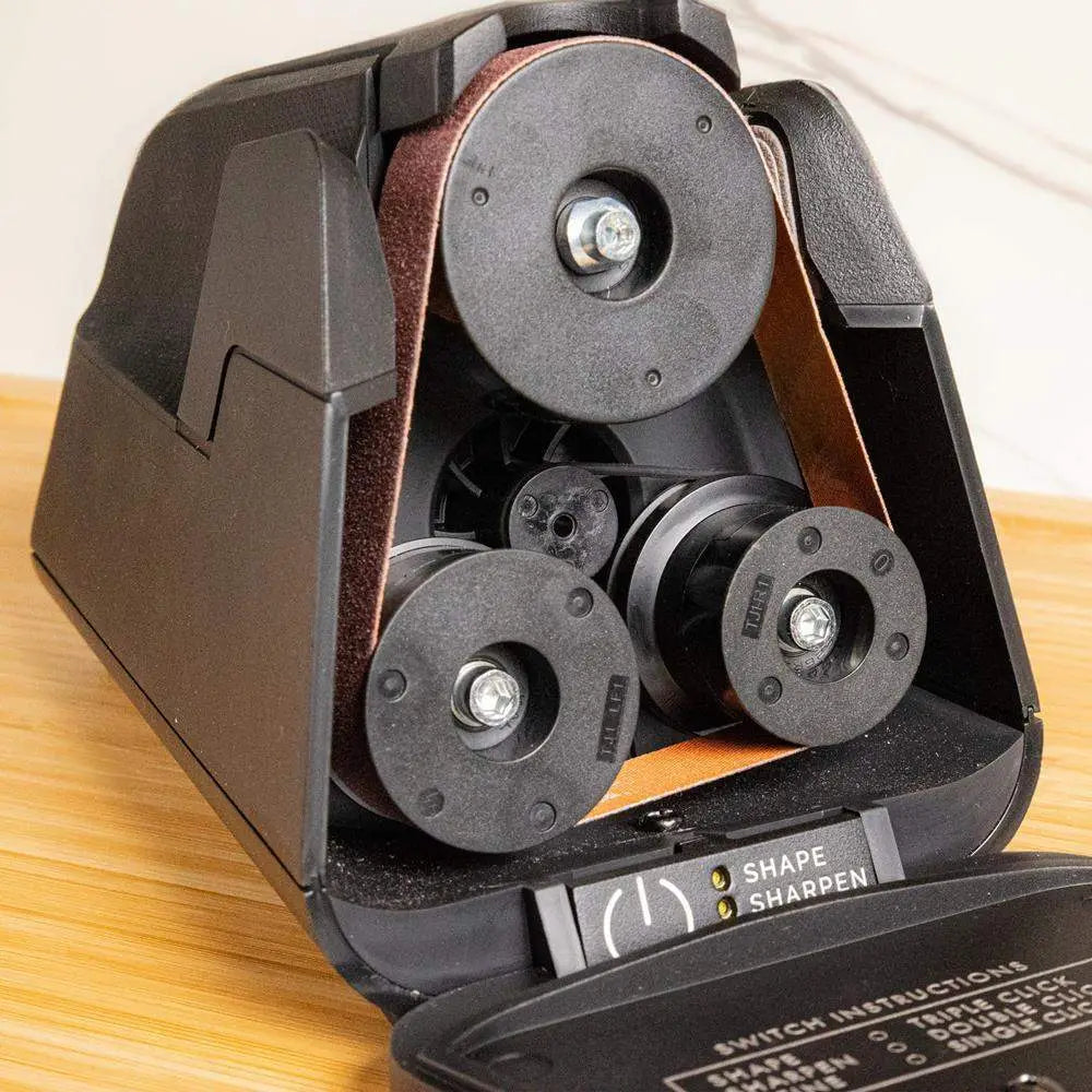 Close-up of a knife sharpener with multiple wheels on a wooden surface.