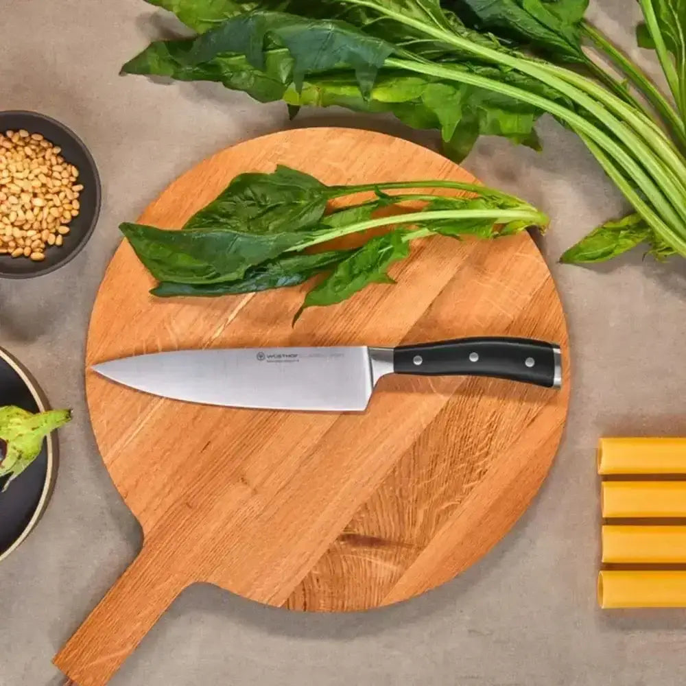 Wooden cutting board with spinach and a knife on a gray surface