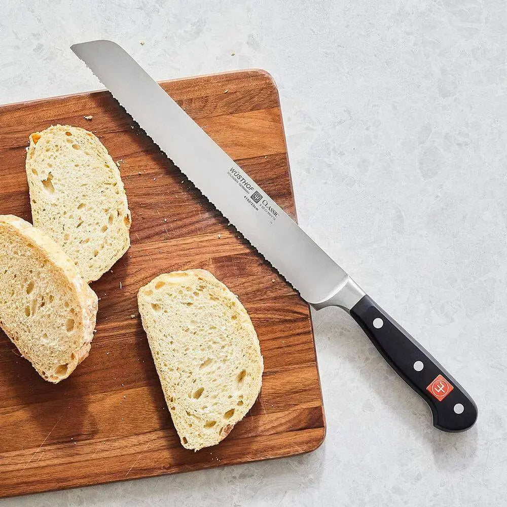 Sliced bread on a wooden cutting board with a Wusthof serrated bread knife