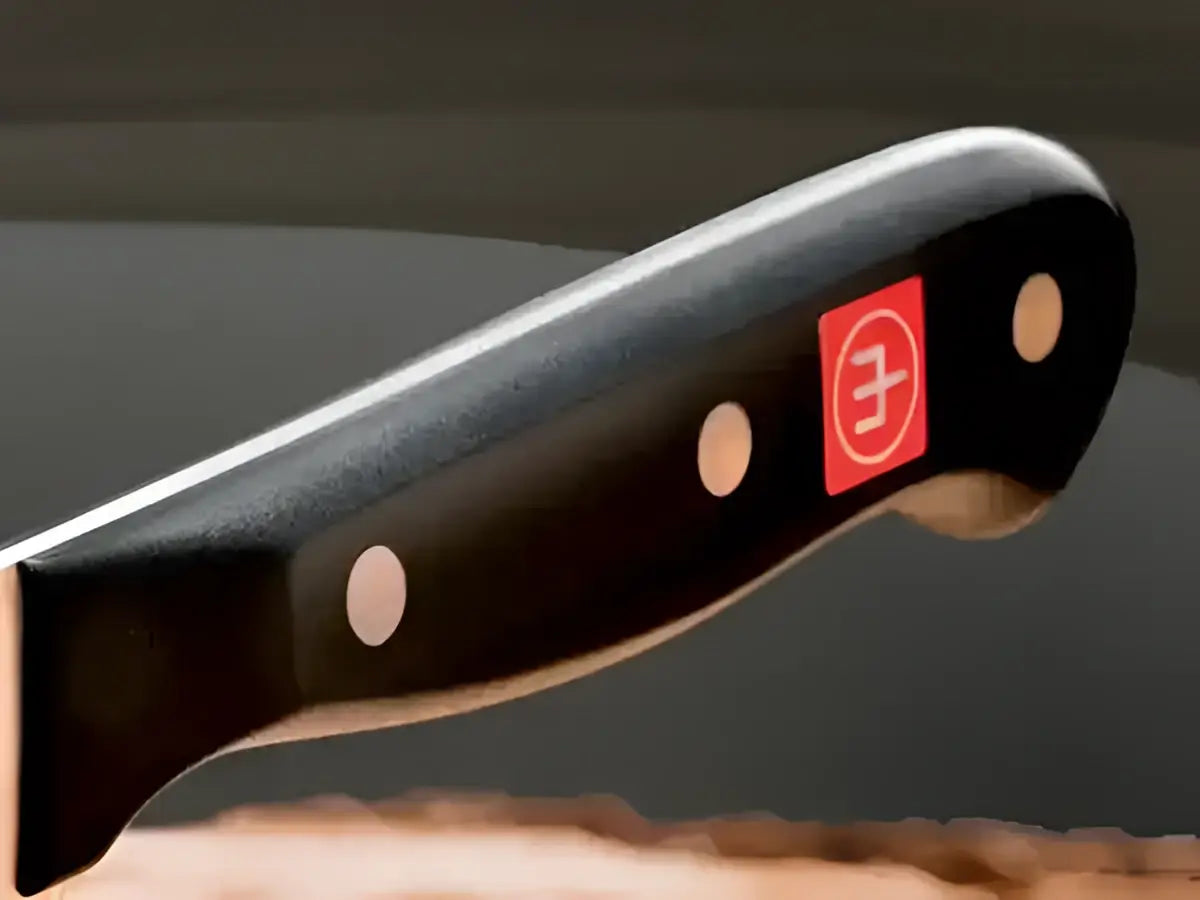 Knife handle with a brand logo on a dark background