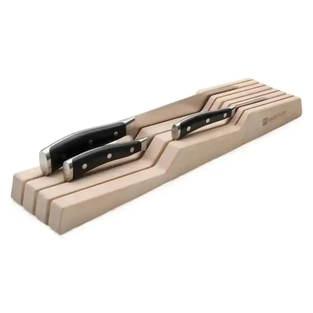 Set of knives with black handles on a wooden block against a white background