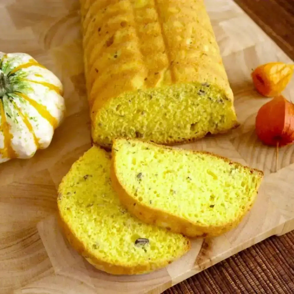 Loaf of yellow bread with slices on a wooden surface with pumpkins.