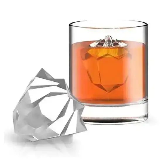 Glass of amber liquid with a diamond-shaped ice cube next to it on a white background