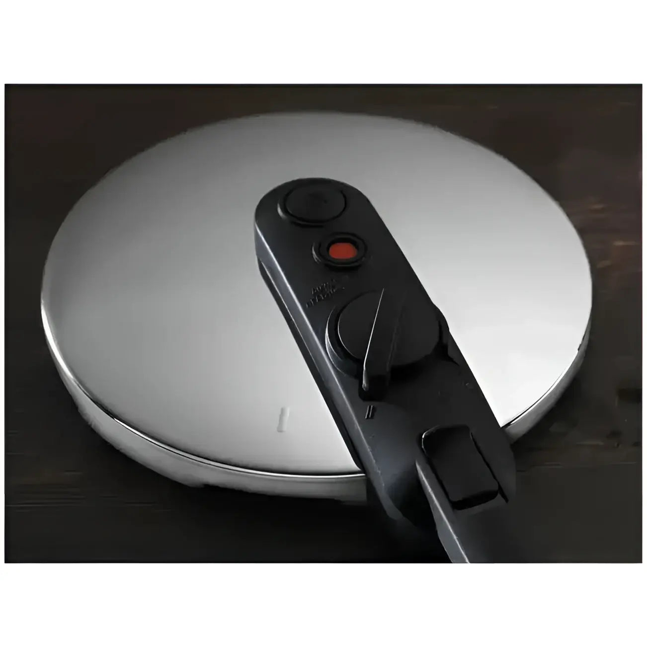 Close-up of a pressure cooker lid with a release valve on a wooden surface