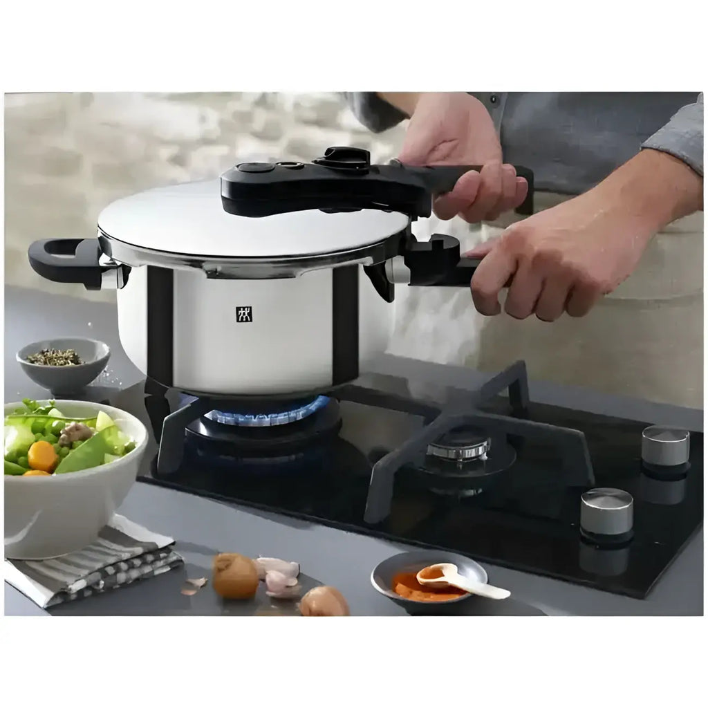 Person using a pressure cooker on a gas stove with ingredients around