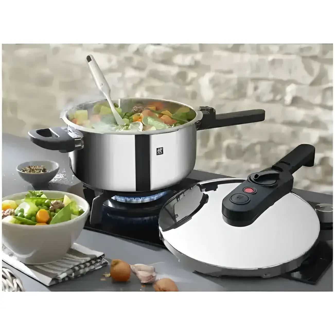 Stainless steel pot with food on a gas stove, next to a pressure cooker and bowls of salad.