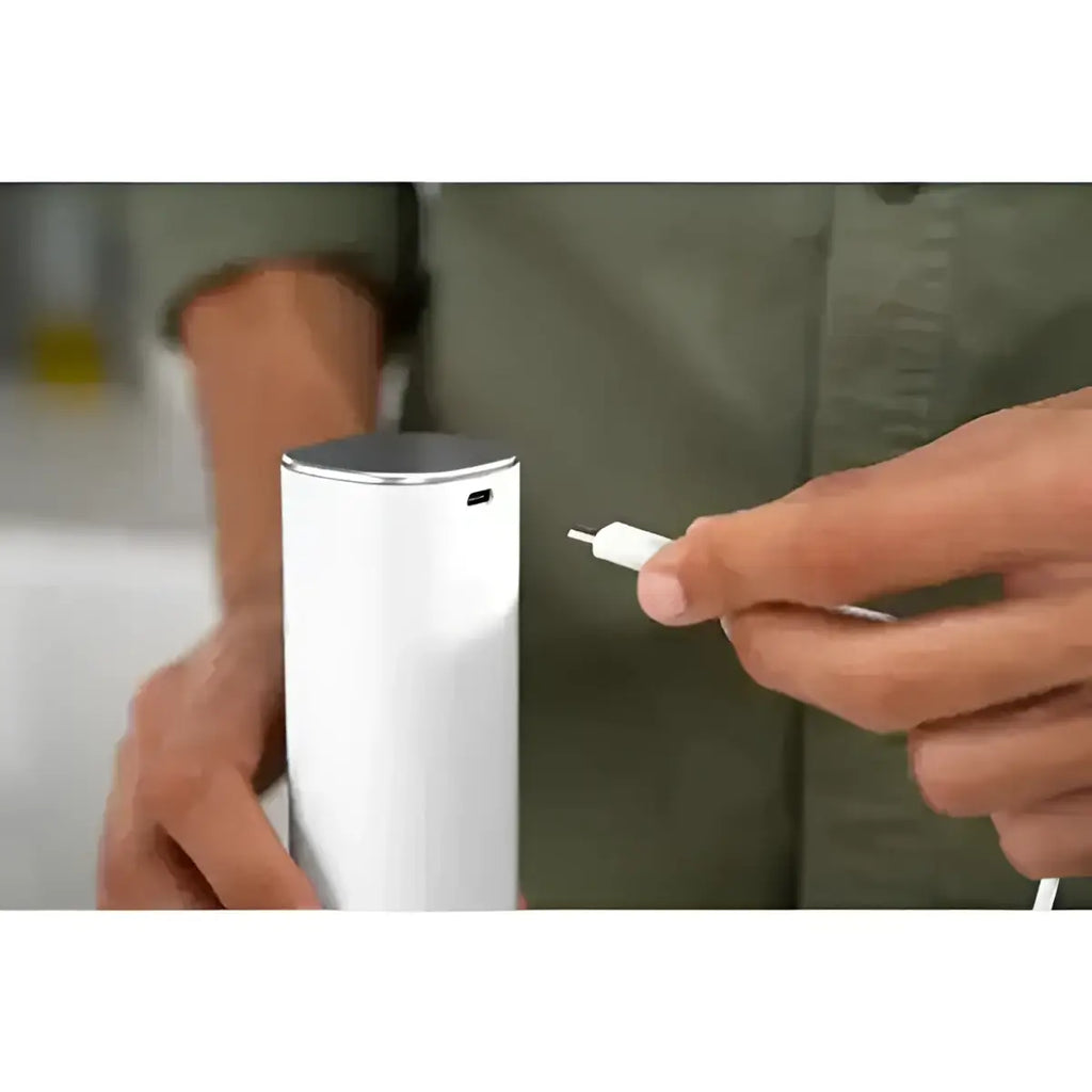 Person holding a white cylindrical device with a charging cable