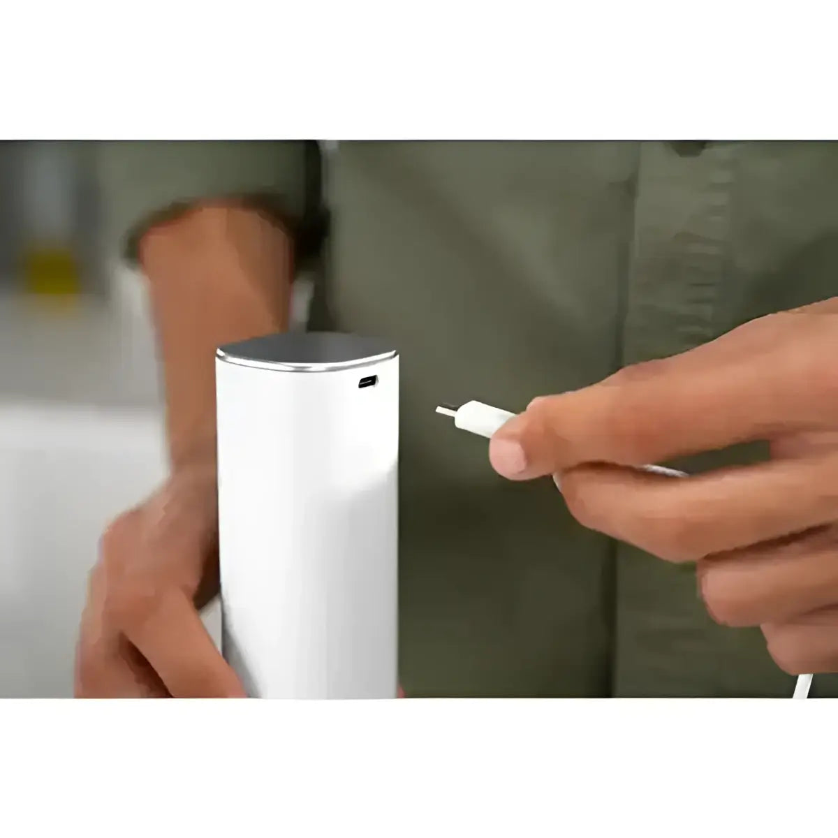 Person holding a white cylindrical device with a charging cable