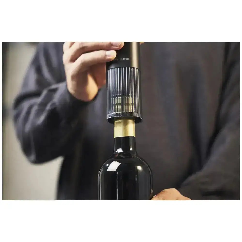Person using a wine bottle stopper on a dark bottle with a blurred background