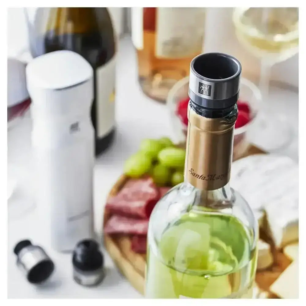 Wine bottle with a wine stopper on a table with food and wine bottles in the background