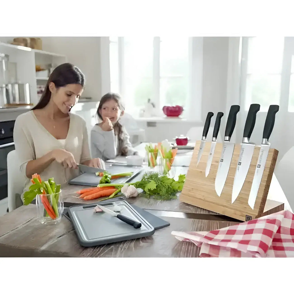 Woman and child preparing food in a kitchen with knives and cutting boards.
