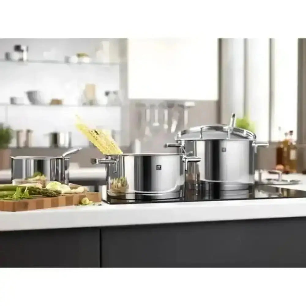 Stainless steel cookware set on a kitchen counter with a blurred background