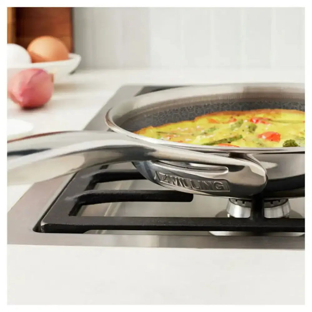 Frying pan with omelette on a stove, surrounded by kitchen items.