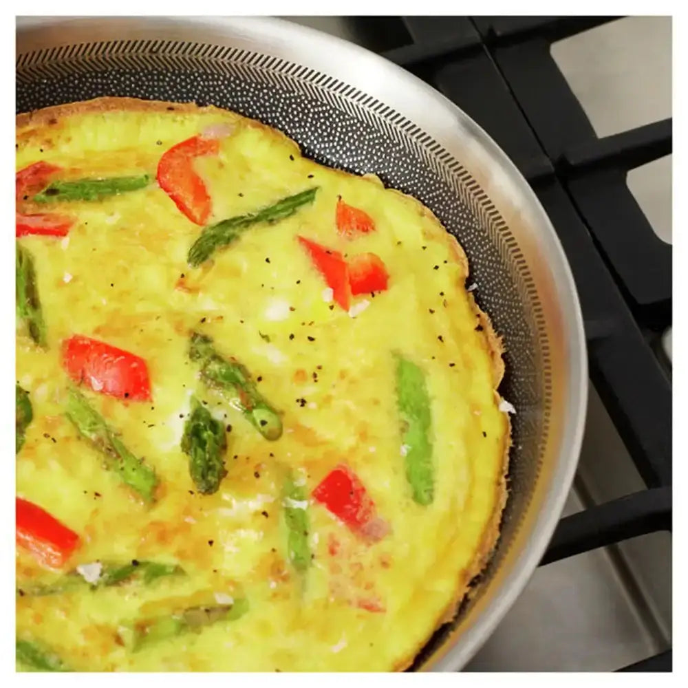 Vegetable frittata with red peppers and green asparagus in a frying pan.