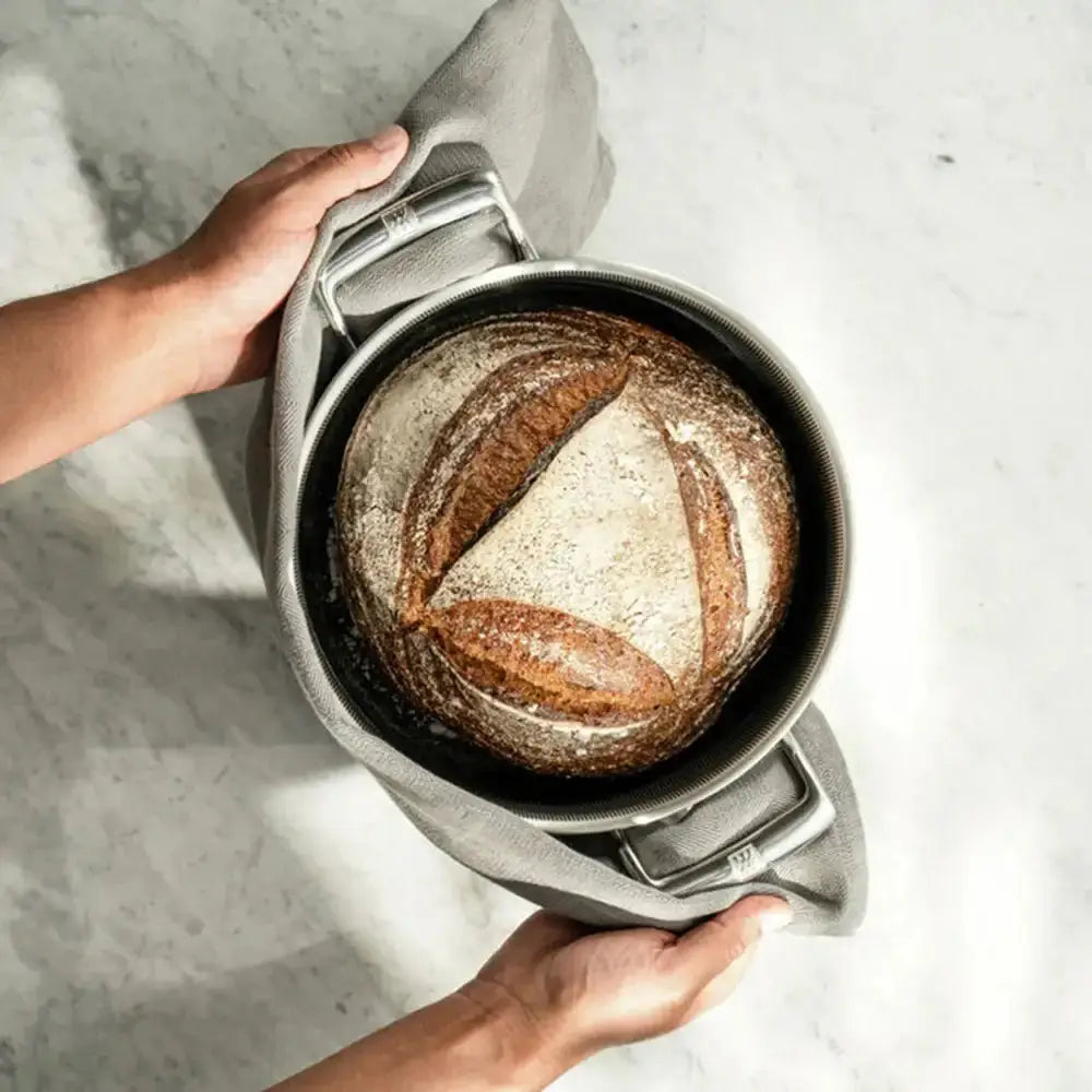 Person holding a metal container with bread inside on a light background