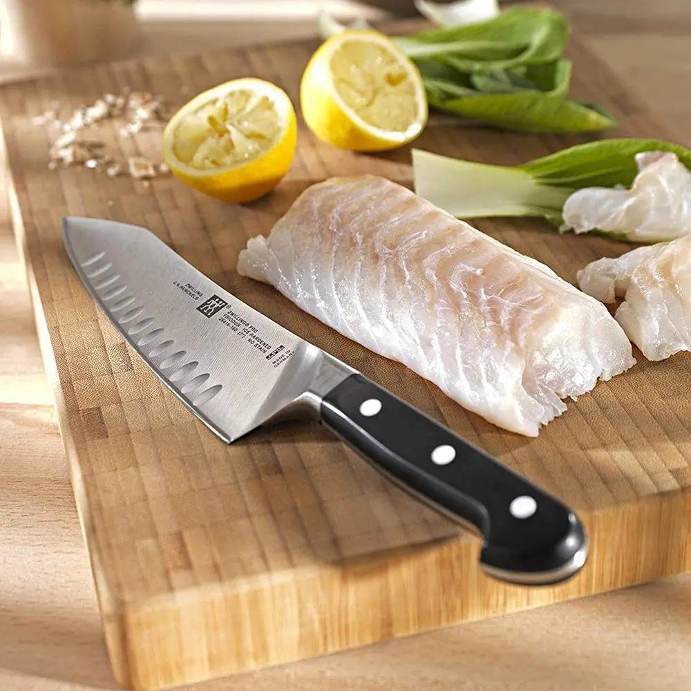 Chef's knife on a wooden cutting board with fish fillets and lemons