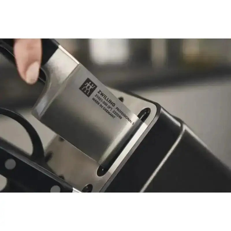 Knife with a visible brand label held by a hand against a blurred background