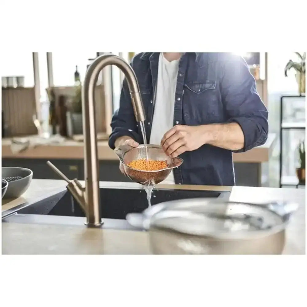 Person washing carrots under a kitchen faucet with a modern kitchen setting.